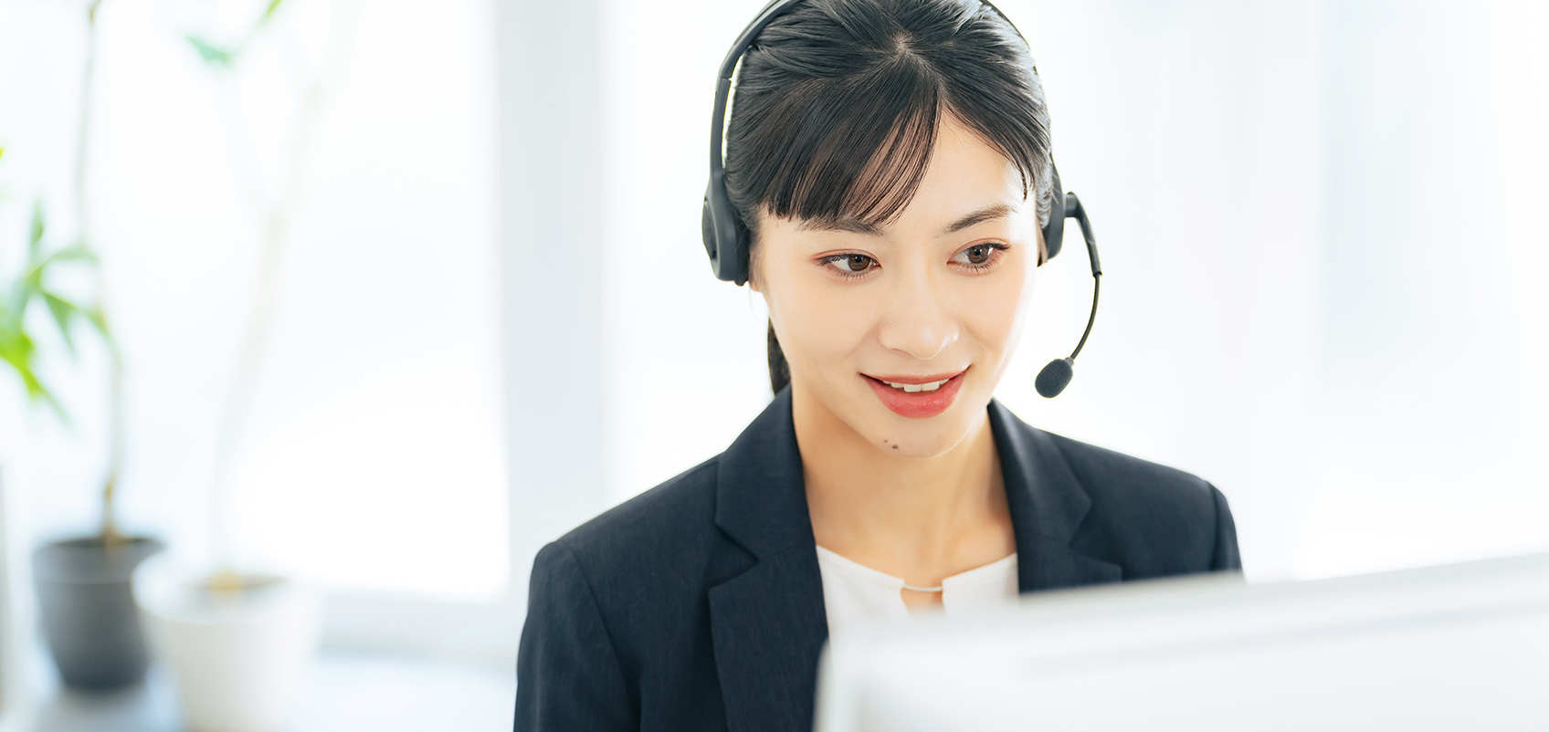 An illustration of a customer support representative wearing a headset and assisting at a computer.